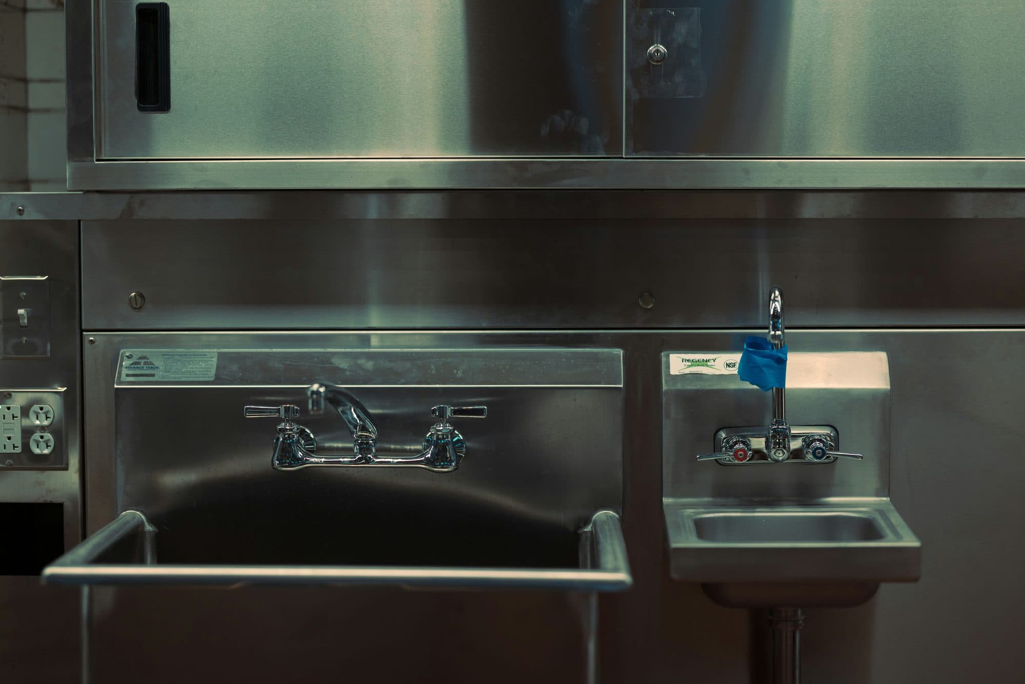 A restaurant kitchen with a stainless pre-rinse sink and hand-wash sink